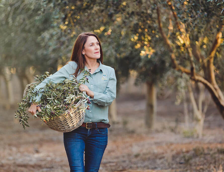 Natasha DalBon carrying a basket of olive trimmings from the olive trees in the grove